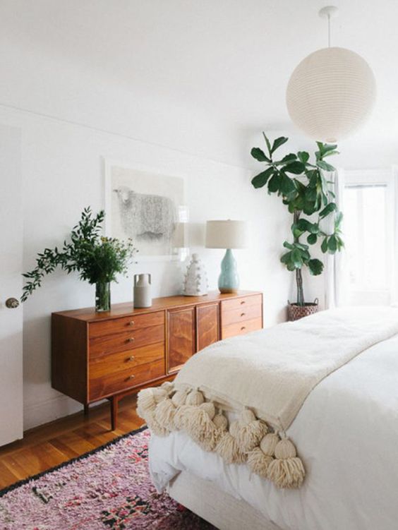 A light filled and chic neutral bedroom done in mid century modern style and refreshed with much greenery
