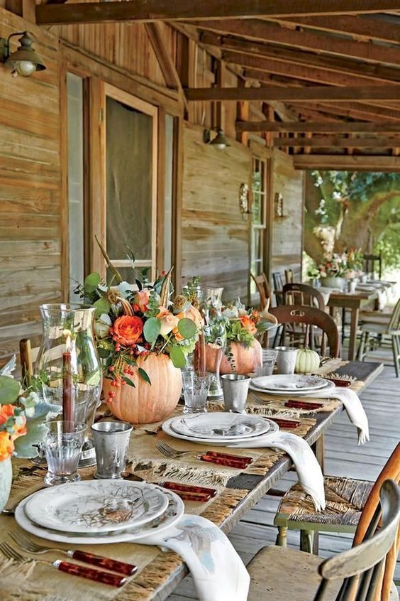 natural fall centerpieces with pumpkin vases, orange blooms, feathers and greenery for Thanksgiving