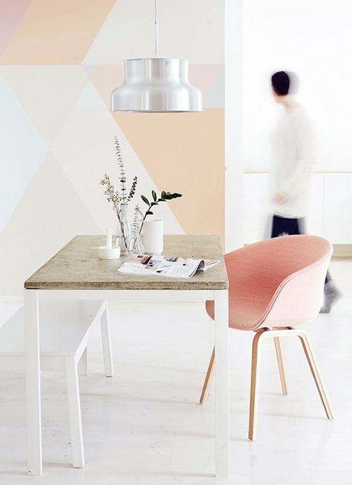 a feminine home office with a geometric color block wall in pastel shades plus a matching pink chair