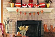 a mantel with colorful pumpkins, a fall leaf banner,potted plants and a faux horse head with a scarf
