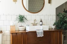 04 a mid-century modern bathroom with subway tiles, a wooden vanity and much potted greenery