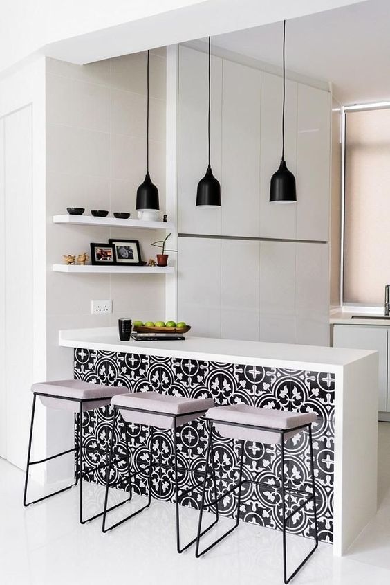An all white minimalist kitchen enlivened with bright black and white printed tiles on the kitchen island