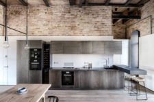 05 The kitchen is done with dark metal cabinets and a floating breakfast space with stools