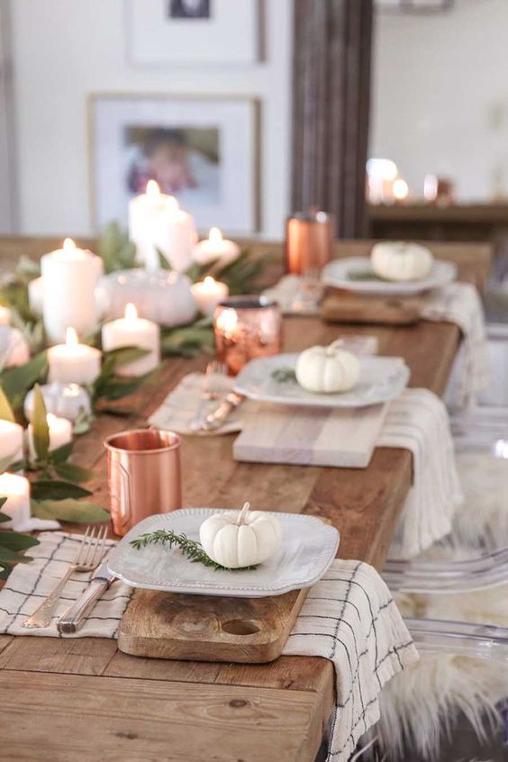 a natural tablescape with cutting boards, white pumpkins, greenery and copper mugs for a chic touch