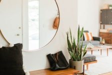 05 an airy mid-century modern entryway with an oversized round mirror and a cool bench