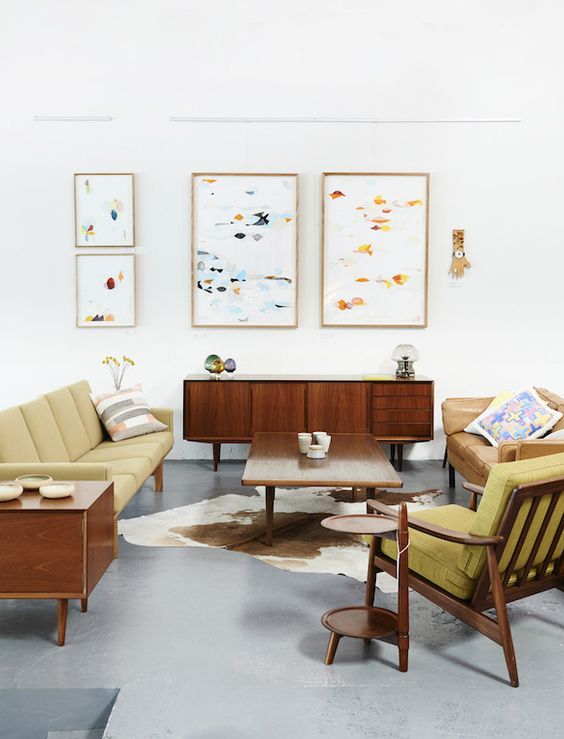 a bright mid-century modern living room with mustard colored furniture and abstract paintings