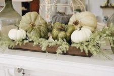 06 a farmhouse styled Thanksgiving decoration of a wooden crate, greenery, white and green pumpkins and a fake cage