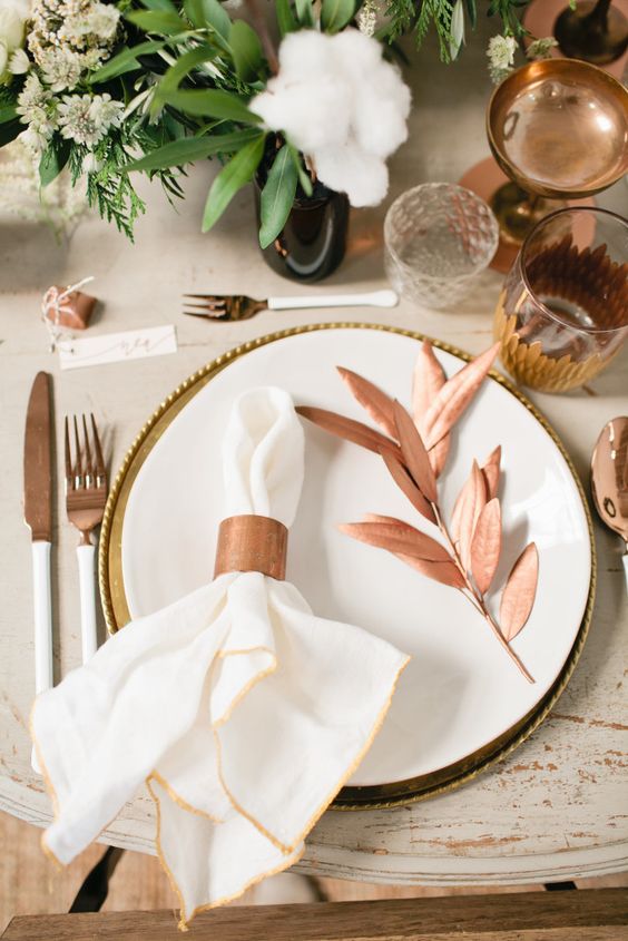 a copper napkin ring, cutlery, glasses and a faux leaf copper branch for a chic Thanksgiving place setting