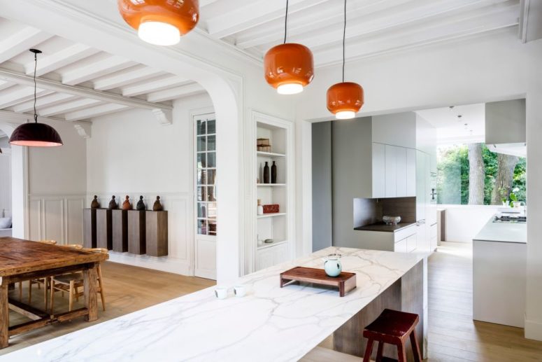 The kitchen features minimalist cabinets, a large kitchen island and a vintage dining set