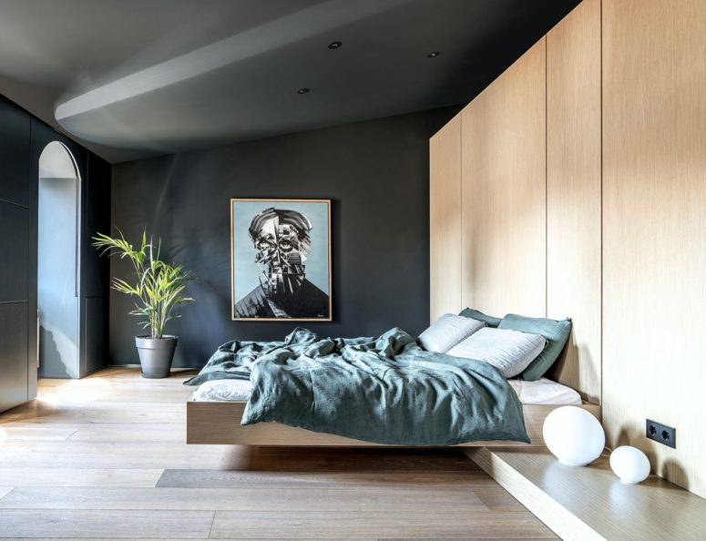 The large master bedroom shows off much storage and a floating bed, dark walls and a large artwork