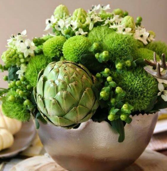 a chic fresh green Thanksgiving centerpiece of green blooms, berries, an artichoke and white flowers