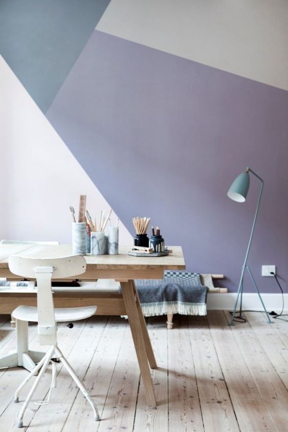 a gorgeous geometric color block wall with blush, lavender and grey plus a blue lamp