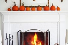08 a simple rustic mantel with an arrangement of orange pumpkins and a wheat wreath on the mirror