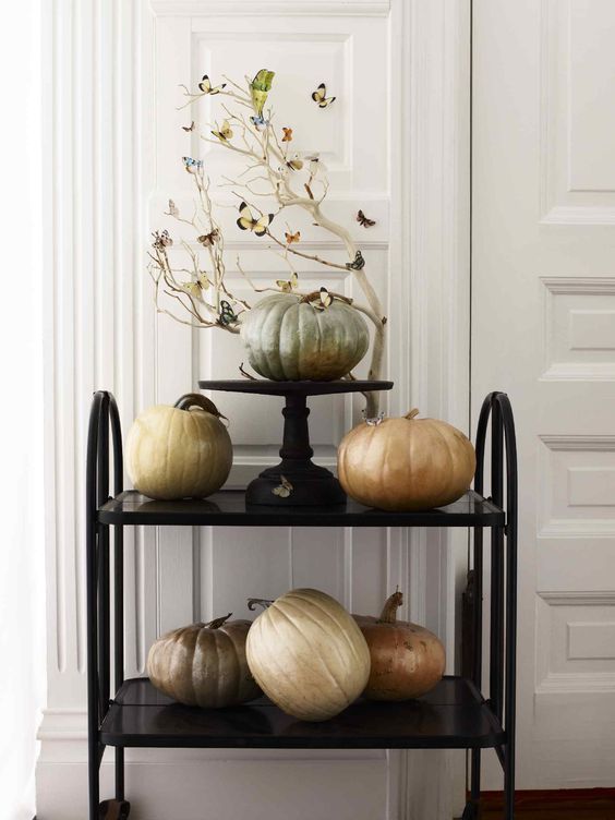 a black cart with pumpkins painted with pearly paint and whitewashed branches for Halloween