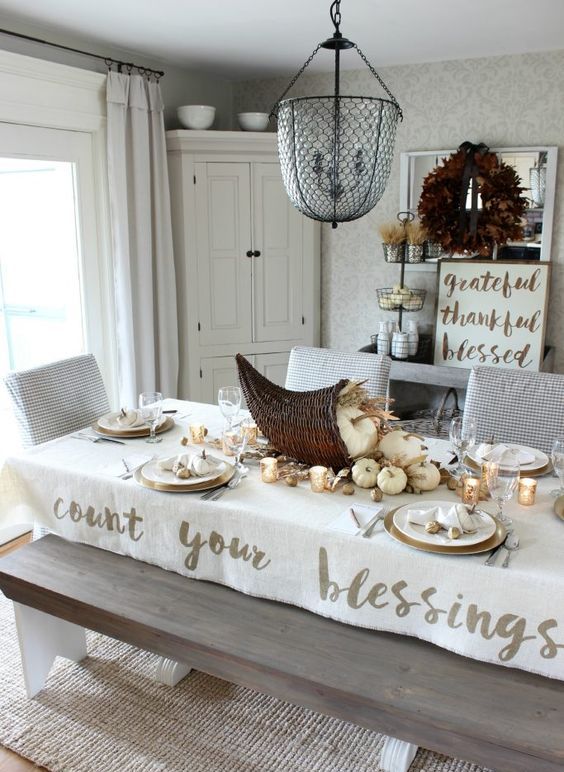 a rustic Thanksgiving table setting with neutral pumpkins, wheat and a cornucopia centerpiece