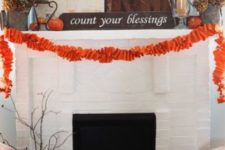 10 a large pallet, some orange pumpkins, an orange fabric garland and dried hydrangeas and firewood in the fireplace