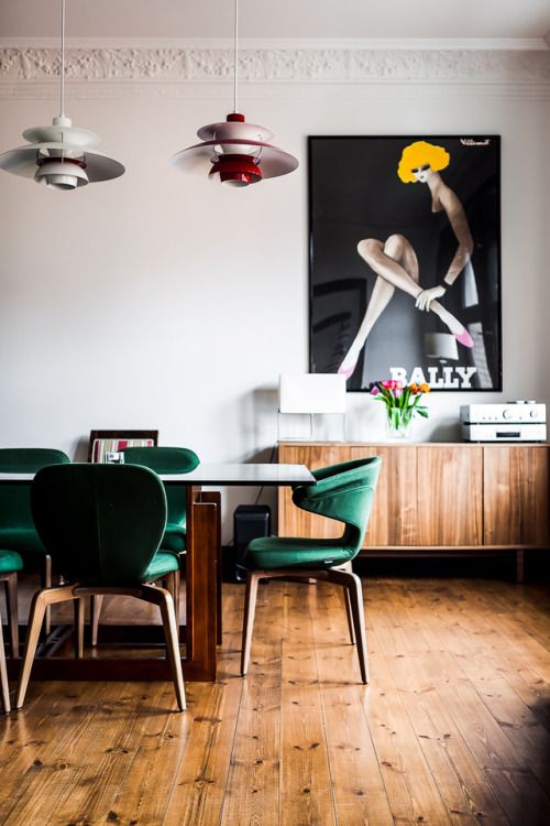 a mid-century modern dining room with emerald chairs with an oversized poster for a statement
