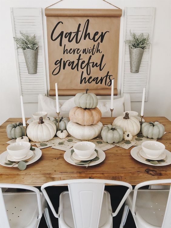 a natural table setting with candles and heirloom pumpkins plus a book page table runner and white porcelain