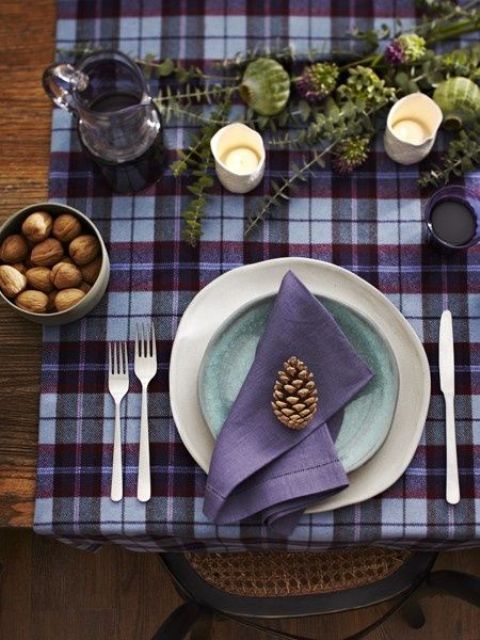 a plaid purple and burgundy tablecloth, a purple napkin, a blue plate and a purple glass pitcher look cozy