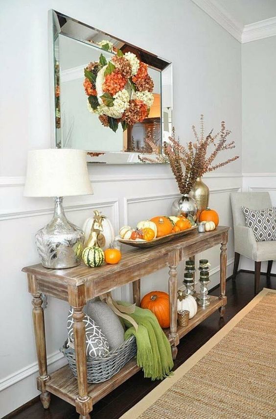 a rustic vintage console with real pumpkins, dried bloom wreaths, herbs, scarves and pillows