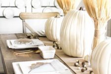 11 a neutral rustic table setting with large pumpkins, wheat, gilded cutlery and white plates, a wheat wreath on the wall