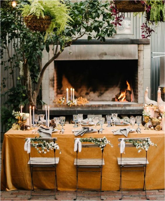 a very cozy table setting placed in a patio with a fireplace, which will keep you warm when it's getting later