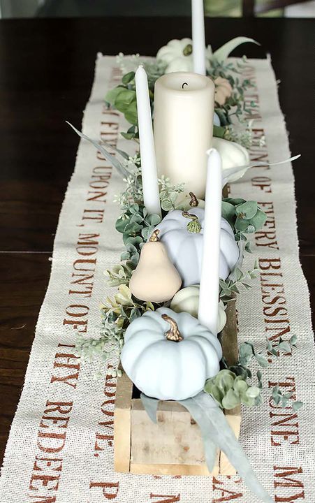 a chic neutral fall or Thanksgiving centerpiece of a wooden box, candles, greenery, faux pumpkins and pears