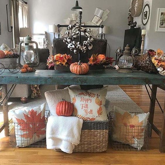a teal rustic console with fall leaves, pumpkins, a cotton wreath and baskets with fall printed pillows