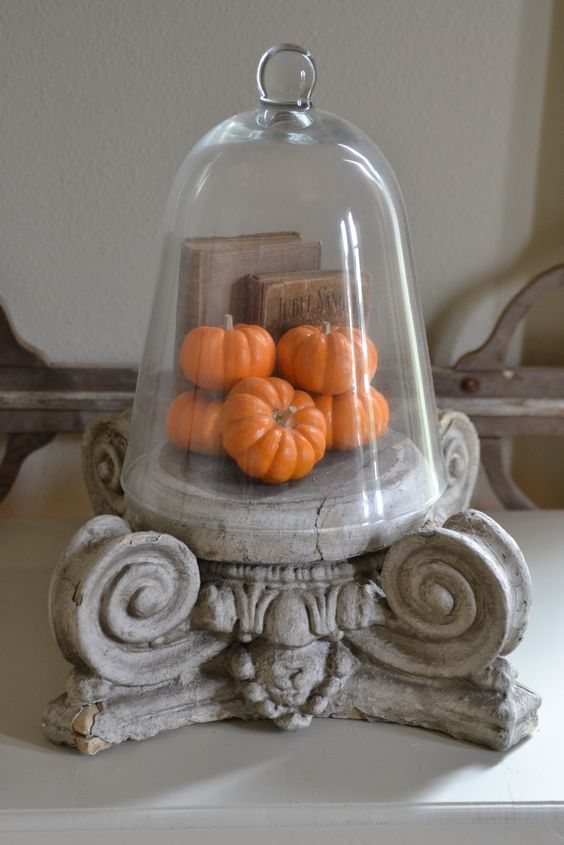 a vintage cloche with fake pumpkins and vintage books is a chic idea for farmhouse, vintage and rustic decor