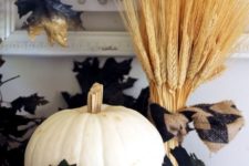 13 wheat, a white pumpkin, a gilded pinecone and some fake black leaves create a dramatic arrangement for Halloween