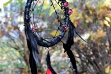 a black dream catcher with black feathers and fake roses looks very witchy and boho-like