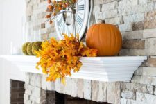 14 a rustic mantel with fall elaves, moss balls, pumpkins and fruits on the branches is suitable for both fall and Thanksgiving