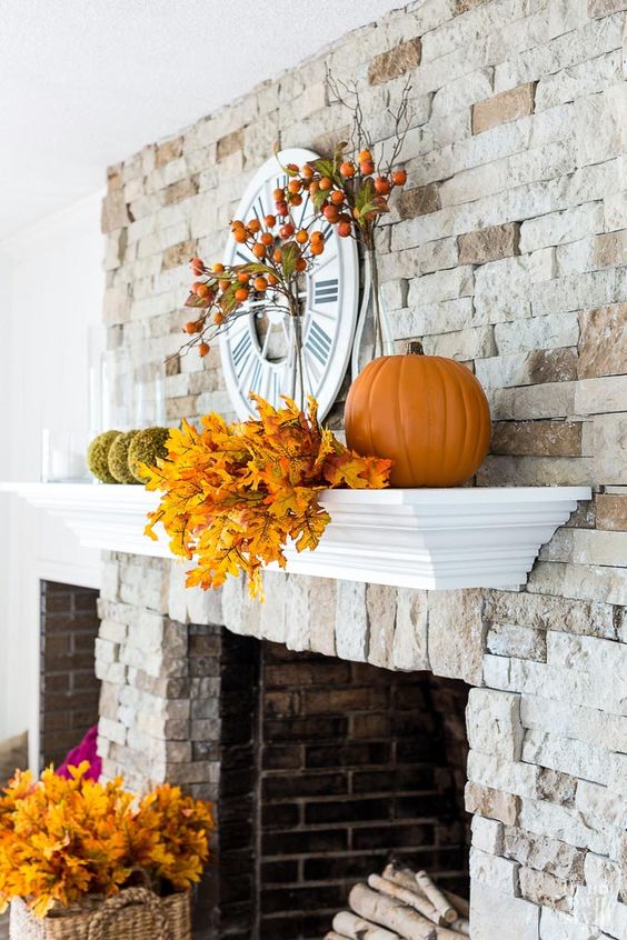 a rustic mantel with fall elaves, moss balls, pumpkins and fruits on the branches is suitable for both fall and Thanksgiving
