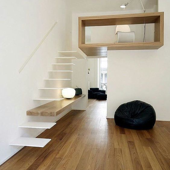 An ultra minimalist staircase with white floating steps and a shelf integrated into the construction