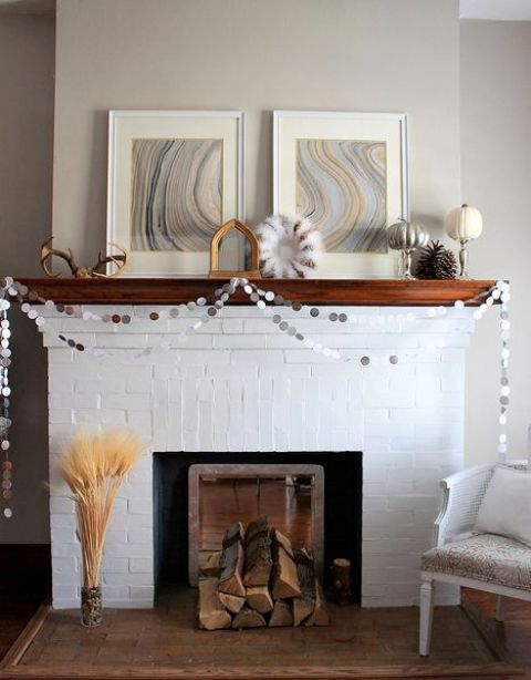 a colorful banner, a cotton wreath, antlers, a pumpkin, firewood and some wheat next to the fireplace