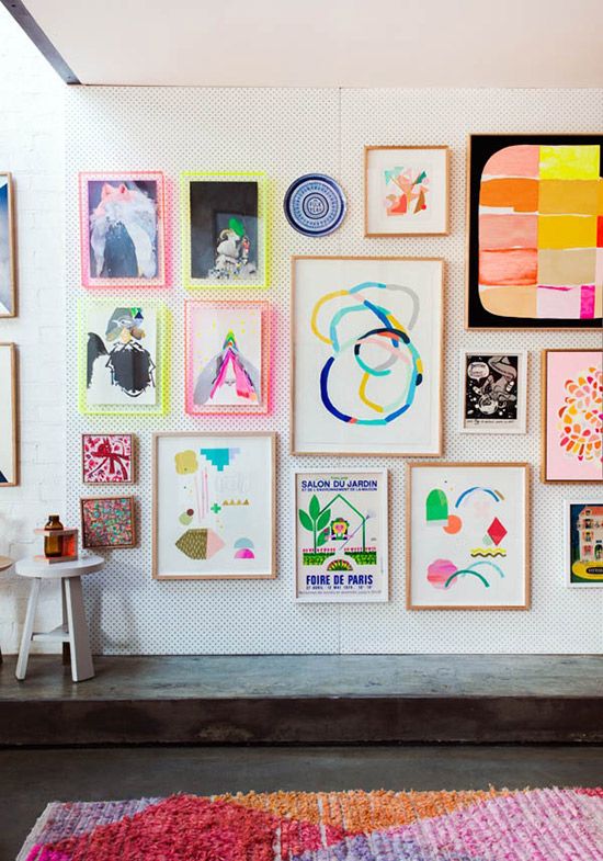 a colorful modern gallery wall with decorative plates,colorful frames and neon touches