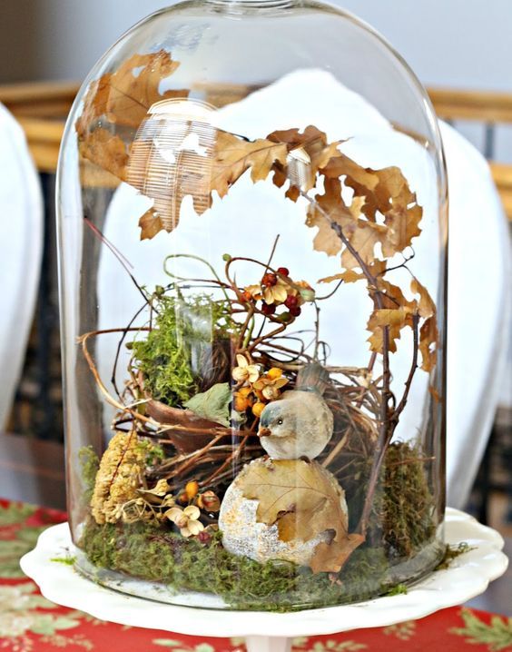 a beautiful fall display with moss, fall leaves, berries,  fake bird and a fake nest of twigs for a rutic feel
