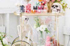 16 a chic vintage Halloween bar cart with skeletons,colorful candies and a bright pink peony centerpiece