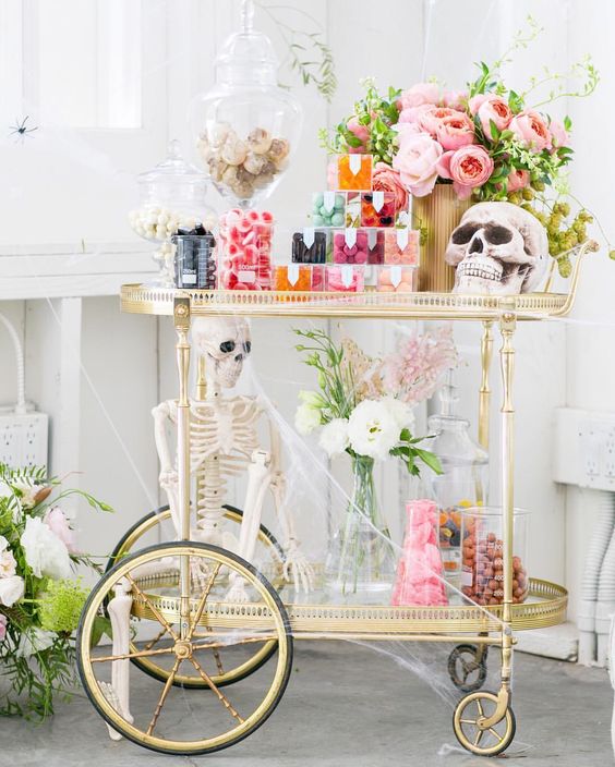 a chic vintage Halloween bar cart with skeletons,colorful candies and a bright pink peony centerpiece