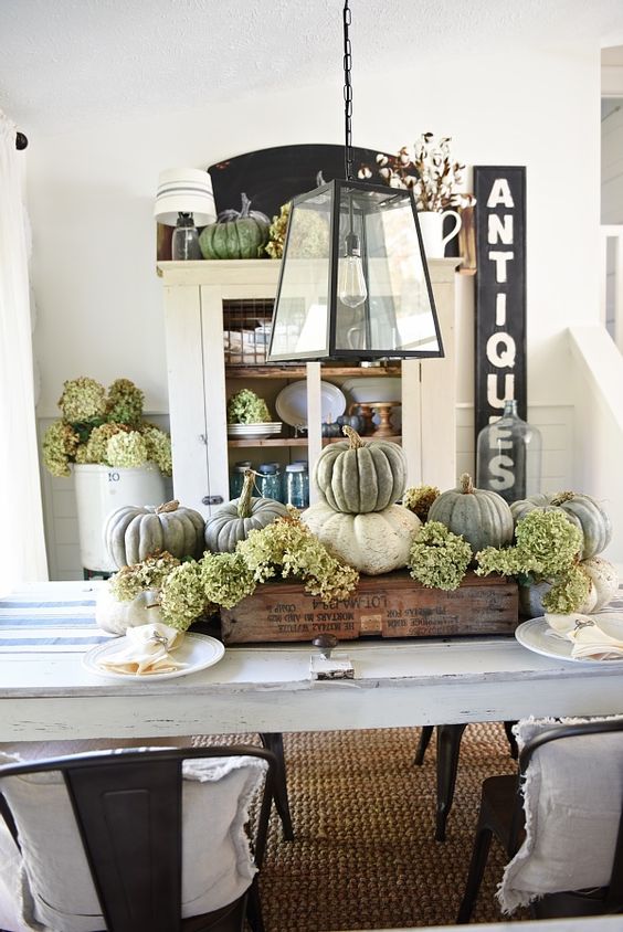 a rustic Thanksgiving centerpiece of white and green pumpkins and green hydrangeas in an industrial crate