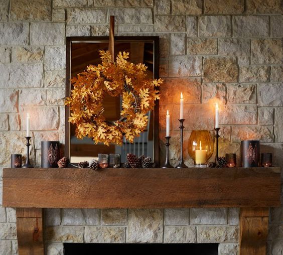 a rustic fall mantel with pinecones, candles, a fall leaf wreath for a cozy and comfy feel