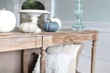 16 a vintage console with faux pumpkins including fabric ones and a basket with pillows and blankets