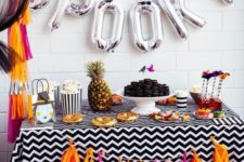 17 a colorful candy bar with a bright tassel garland and silver letter balloons plus a pineapple for a tropical feel