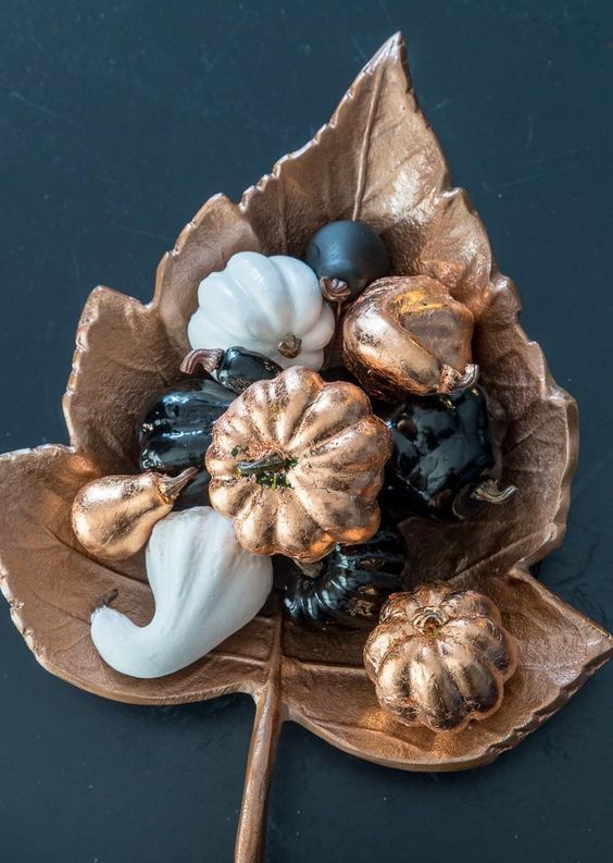 a whimsy fall centerpiece of a copper leaf and black, white and copper faux vegetables for Thanksgiving