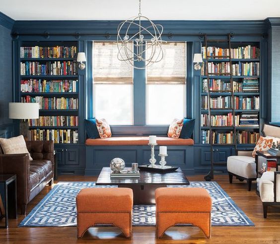 a colorful interior in blue and orange with lots of bookshelves that frame the window