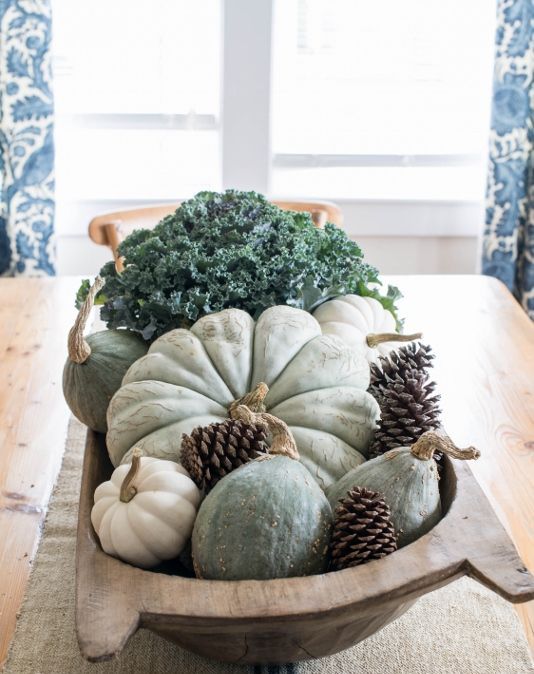 a natural Thanksgiving centerpiece of a bread bowl, pinecones, heirloom pumpkins, gourds and fresh veggies