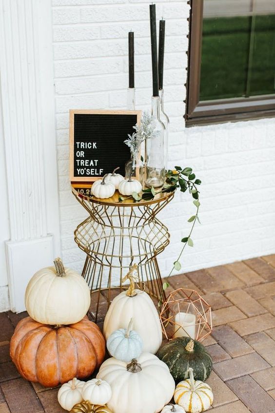 a boho chic outdoor display with a metlalic table, black candles, heirloom pumpkins, greenery and a sign