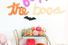 20 a super bright bar cart filled with colorful pumpkins and paper balls, colorful barware and with letters above