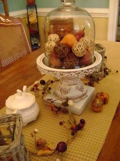 a fall vintage cloche display with fake fruits and twine balls for a rustic and vintage feel