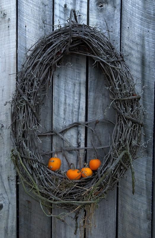 a grapevine wreath with little orange pumpkins is all you need to craft for your front door at Halloween